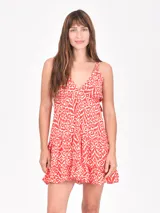 Vestido corto con estampado en tonos rojo y blanco, escote en V y tirantes finos. Presenta un corte holgado con volados en el ruedo.