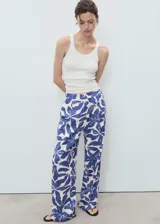 Pantalón tiro medio de corte recto, con estampado floral azul sobre fondo blanco, detalle de pinzas y bolsillos laterales. Cierre oculto con botón, gancho y cremallera.