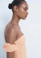 Vestido midi de color durazno, con escote palabra de honor y mangas cortas abullonadas caídas. Presenta un diseño entallado con abertura lateral en la falda y cierre de cremallera lateral.