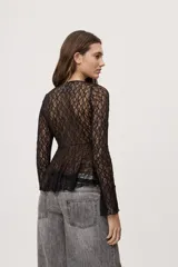 Top de encaje negro semitransparente con escote en V profundo, volados en los bordes y mangas largas. Cuenta con cierre frontal con lazos para anudar y diseño irregular.