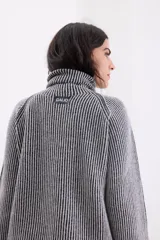 Sweater de cuello tortuga con diseño de rayas verticales en contraste. Presenta mangas largas con hombros caídos y un acabado con sutil brillo de lurex.
