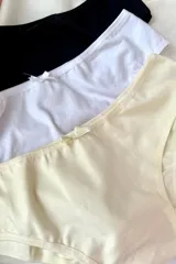 Pack de tres bombachas de algodón elastizado en colores negro, blanco y beige, con moño decorativo en el centro.