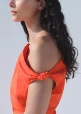 Vestido corto de algodón color naranja con diseño entallado, cuello asimétrico y fruncidos laterales.
