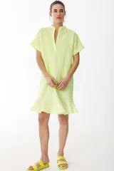 Vestido amarillo flúor de corte recto, largo hasta la rodilla, con cuello mao y mangas cortas. Presenta detalle de calados con forma de flores en el cuello, mangas y ruedo.