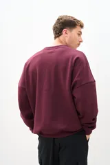 Buzo de cuello redondo color bordó, de corte amplio y mangas largas.