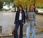Chaqueta de denim estilo militar con diseño napoleónico, caracterizada por su doble fila de botones metálicos decorativos en el frente y mangas acampanadas con detalles de botones en los puños. Presenta un corte entallado y cuello redondo.