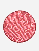 Pareo circular de algodón con estampado geométrico en tonos rojos, rosados y blancos, con flecos en el borde.