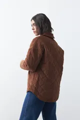 Campera capitoneada de algodón con diseño matelaseado, cuello camisero y cierre frontal con botones a presión. Presenta un corte relajado y bolsillos frontales.