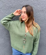Buzo tejido de punto color verde militar, con escote en V pronunciado, mangas largas y corte holgado.
