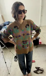 Buzo tejido de algodón con diseño jacquard de flores en tonos verdes y morados sobre base marrón, con escote en V y puños y dobladillo acanalados.