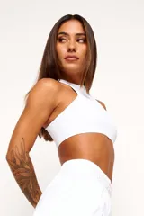 Top deportivo de cuello alto, confeccionado en tejido de poliamida y elastano. Presenta un diseño minimalista, ajuste al cuerpo y forro interno para mayor soporte.