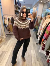 Sweater de punto tejido a mano con diseño de guarda nórdica en la parte superior, cuello redondo y mangas largas. Presenta una combinación de colores en tonos marrón oscuro, beige y blanco.