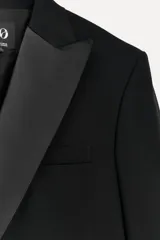 Blazer negra cruzada con solapa de muescas en tejido combinado a tono, bolsillos con solapa en delantero y de vivo en pecho, y abertura en espalda.