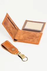 Set de billetera y llavero de cuero color marrón. La billetera es de cuero liso con costuras a tono y el llavero es de cuero texturizado con botón a presión y mosquetón metálico.