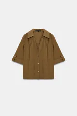 Camisa marrón con textura, cuello solapa, escote en V y cierre frontal con botones. Mangas cortas con vuelta y trabilla.