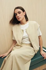 Chaleco color beige sin mangas de silueta relajada, con escote redondeado, cierre frontal con cremallera y ruedo elastizado.