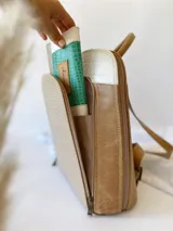 Billetera de cuero con diseño tricolor en tonos turquesa, blanco y beige, con textura tipo reptil. Cuenta con una solapa frontal con cierre de broche y una etiqueta de cuero con el logo grabado.