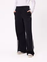 Pantalon de jogging de corte ancho, color negro con rayas laterales blancas. Posee cintura elastizada con cordón de ajuste y logo bordado en la parte frontal.