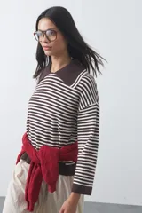 Sweater de punto a rayas horizontales en color bordó y celeste, con cuello polo y mangas largas con puños amplios. Presenta un diseño de calce relajado.