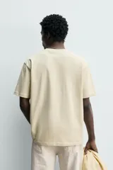Camiseta regular fit de color beige, confeccionada en tejido de algodón compacto, con cuello redondo y manga corta.