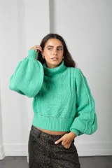 Polera de punto color verde menta, con cuello alto, mangas globo y diseño de trenzas en el frente.
