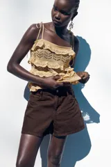 Shorts de jean color marrón oscuro, de tiro medio y corte mom fit. Con cinco bolsillos, cierre frontal con cremallera y botón.