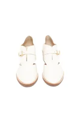 Zapato de cuero color blanco hueso con diseño de texturas combinadas, presentando un acabado tipo reptil en la parte trasera y cuero liso en la puntera. Cuenta con un corte lateral, cierre mediante hebilla dorada y tacón cuadrado de madera.