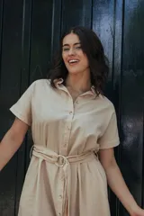 Vestido camisero midi a rayas verticales azules y blancas, con cuello camisero, mangas cortas, cierre frontal con botones y cinturón de la misma tela con hebilla.