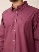 Camisa de manga larga en color azul, confeccionada en algodón con técnica de teñido garment dye. Presenta cuello abotonado, cierre frontal con botones y un bolsillo en el pecho con detalle bordado.