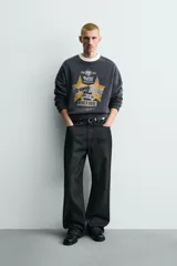 Sudadera de corte boxy fit en color gris oscuro con efecto lavado. Presenta cuello redondo en contraste color crema, manga larga con puños acanalados y estampado gráfico frontal con estrellas y tipografía estilo vintage.