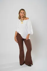 Pantalón de tiro alto con corte evasé, confeccionado en tela color marrón. Presenta costuras verticales decorativas a lo largo de las piernas, cierre frontal con cremallera y botón, y bolsillos funcionales en la parte delantera y trasera.