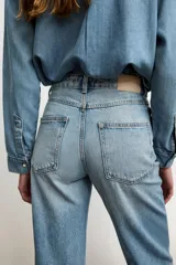 Jeans celeste de tiro alto, corte recto y largo, con cinco bolsillos y cierre frontal con cremallera y botón.