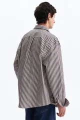 Camisa de algodón suave con cuello inglés, tapeta clásica y canesú en la espalda. Modelo de manga larga con puños abotonados y bajo levemente redondeado. Presenta diseño a rayas en tonos marrón y blanco.