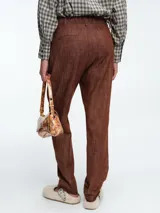 Pantalón de corte recto y tiro medio, confeccionado en denim de algodón con acabado texturizado en color tabaco. Presenta cierre frontal con botón y bolsillos laterales.