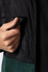 Campera de polar con recortes en tela técnica tipo sire en la parte superior frontal. Presenta cierre frontal completo, cuello alto y bolsillos funcionales en el pecho. Diseño bicolor en tonos verde oliva y negro con logo de la marca en el pecho.