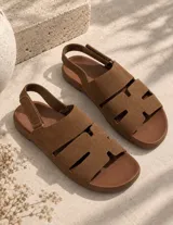 Sandalias planas de gamuza beige, con tiras anchas en el empeine con aberturas y correa ajustable con cierre de velcro en el talón.