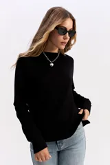 Sweater de punto negro con cuello redondo, manga larga y calce relajado. Presenta una costura vertical central en el frente y puños acanalados.