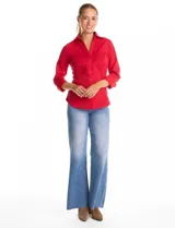 Camisa entallada de color rojo, con cuello solapa, escote en V y cierre frontal con botones. Presenta una pechera con alforzas horizontales y mangas tres cuartos con puños anchos rebatibles.