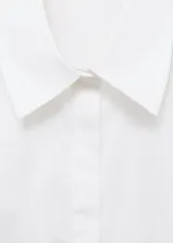 Camisa de popelín de algodón con diseño entallado, cuello camisero, cierre frontal con botones y mangas largas con puños abotonados.