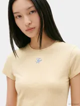 Remera de corte slim color beige, confeccionada en punto de algodón elástico, con cuello redondo y logo texturizado en fuente Script en el pecho.