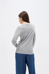 Sweater de lyocell al cuerpo, con cuello redondo a la base y mangas largas con detalle de botones en los puños.