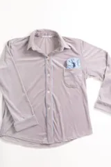 Pijama de dos piezas color rosa pálido, confeccionado en terciopelo. La camisa es de manga larga con botones frontales y bolsillo en el pecho. El pantalón es de corte recto con cintura elástica.