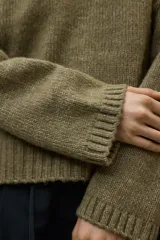 Suéter de punto color beige claro jaspeado, de corte holgado y cuello redondo. Presenta un tejido de punto acanalado en el cuello, puños y bajo.