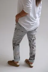Pantalón de corte recto con cintura elástica y cordón ajustable, confeccionado en tela con estampado floral en tonos grises y blancos sobre base celeste.