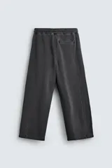 Pantalón jogger de corte wide fit confeccionado en tejido de algodón con interior de rizo. Presenta cintura elástica ajustable con cordón, bandas laterales decorativas, bolsillos laterales y un bolsillo trasero de plastrón. El acabado presenta un efecto lavado que le otorga una apariencia única.