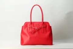 Cartera shopper negra de cuero sintético con asas largas para el hombro, detalles de correas frontales con hebilla y marca She Mona grabada en el frente.