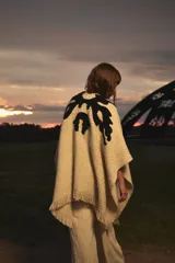 Ruana color crema de tejido grueso con diseño abstracto en negro.