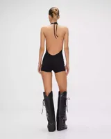 Mono negro ajustado al cuerpo, con escote halter cruzado y abertura en el abdomen.