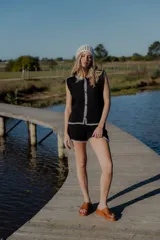 Conjunto tejido de algodón negro con detalles de crochet blanco en los bordes. Incluye un chaleco sin mangas con cierre frontal de botones y un short de tiro alto.