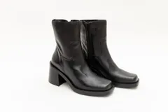 Bota de caña media color negro, de cuero, con punta cuadrada y taco bloque.